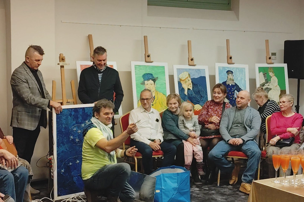 A group photograph of diverse workshop participants, including a person with a guide dog, discussing an art piece.